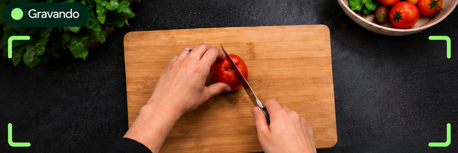 Visão da câmera gravando: mãos cortando um tomate, bem enquadradas